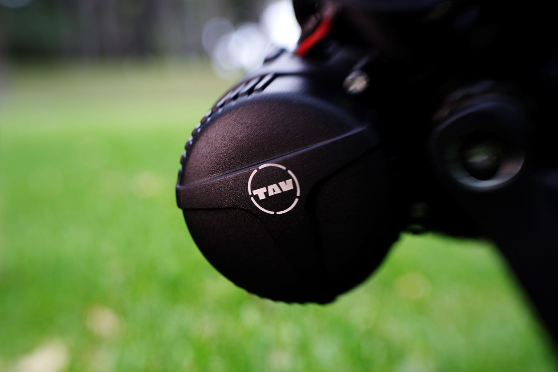 Close-up of the TAV logo on a sleek, black mid-drive motor housing of an e-bike, with a blurred green natural background emphasizing the focus on the detailed craftsmanship.